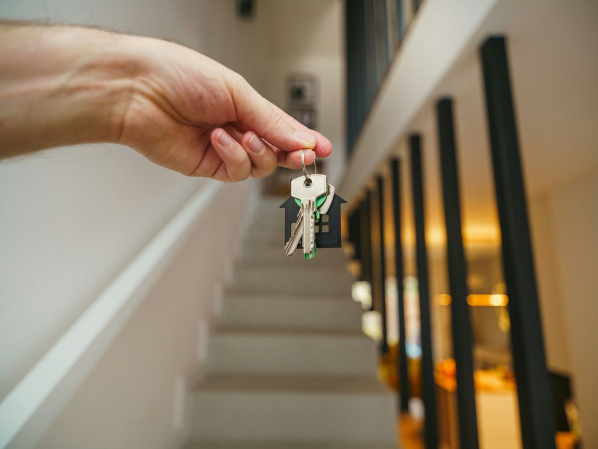 A hand holding house keys with a house-shaped keychain