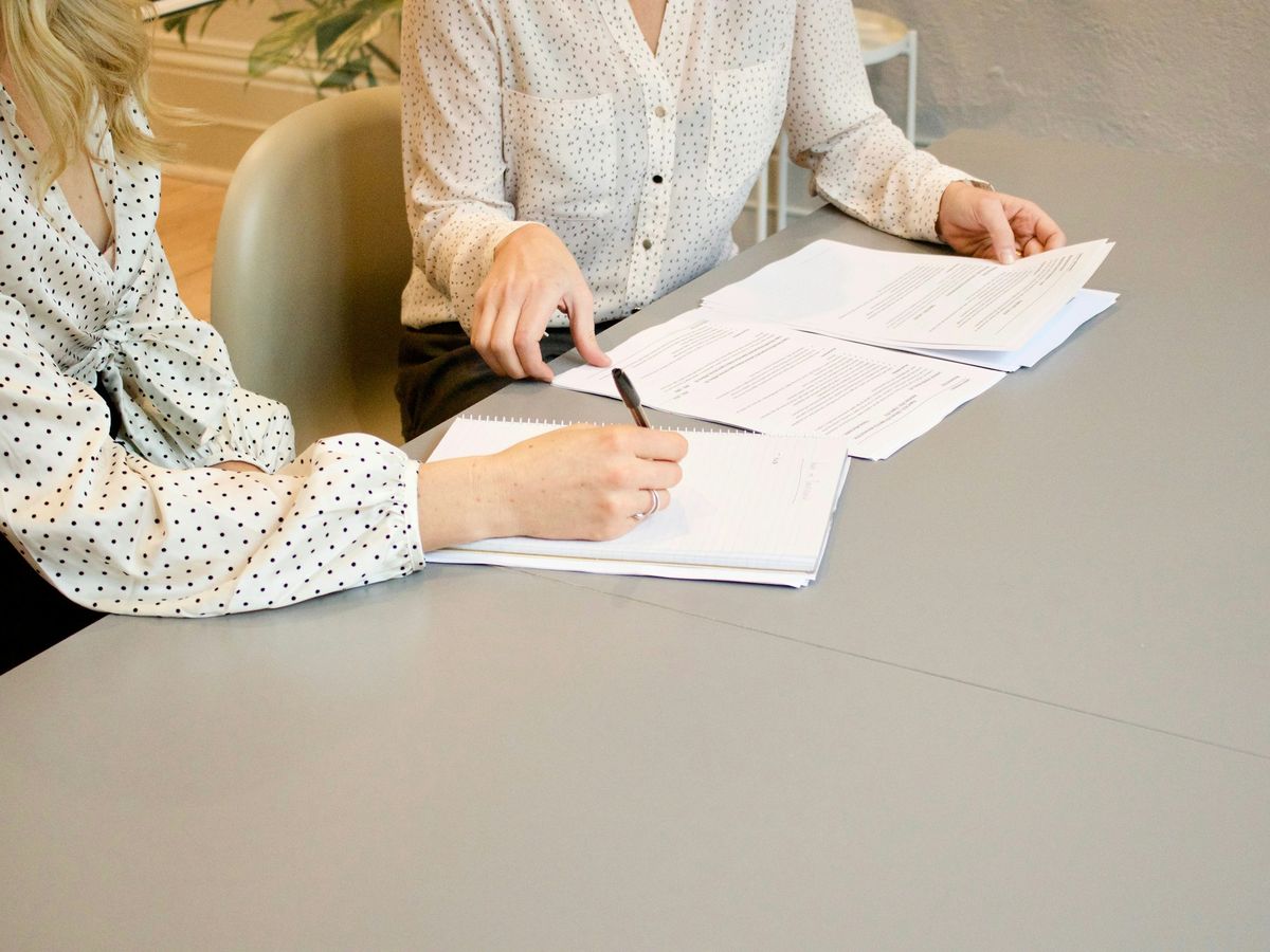 Two people signing loan documents at a table